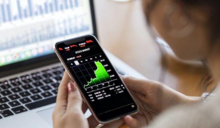 a person holding a smartphone displaying a stock market chart 