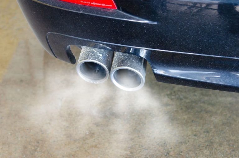 Close-up of a car exhaust pipe emitting visible smoke, illustrating diesel emissions pollution