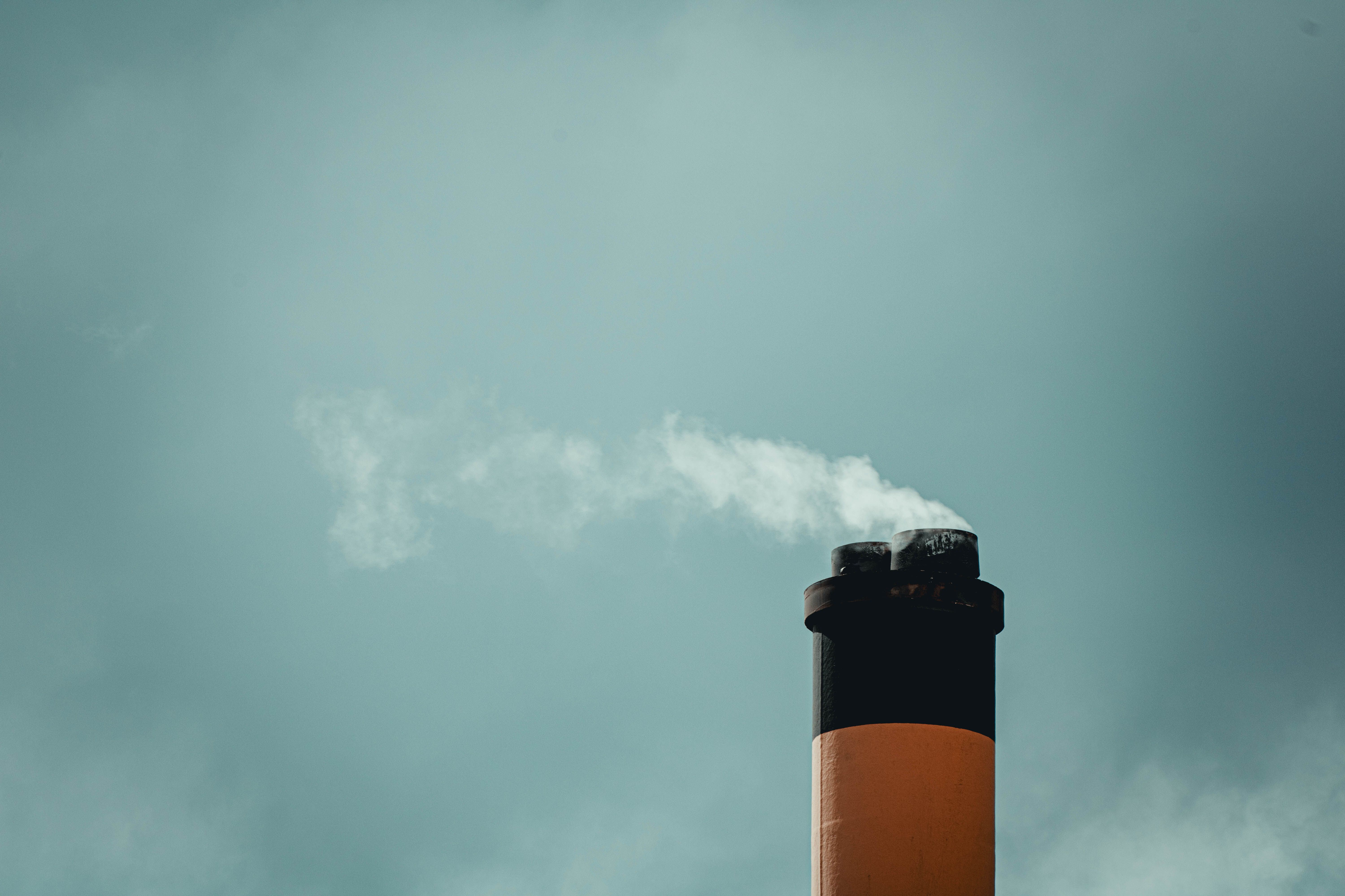 Tall industrial chimney releasing smoke against a cloudy sky, representing diesel and industrial air pollution