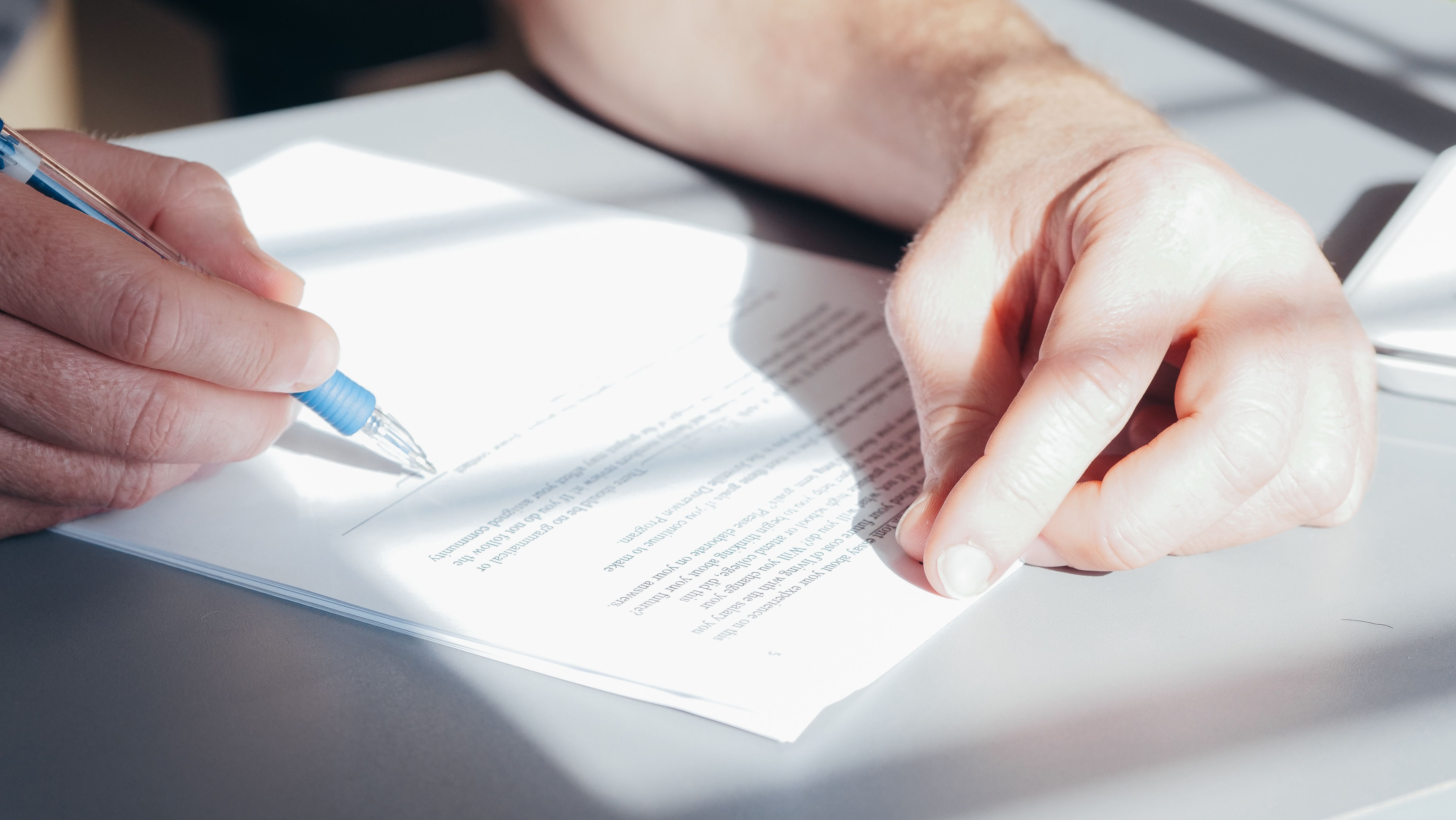 Close-up of a consumer signing an important legal document with a blue pen