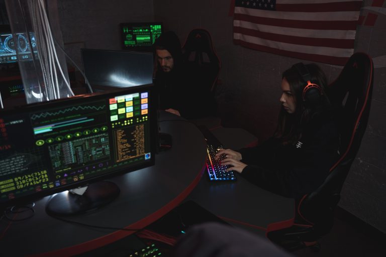 Cybersecurity professionals analyzing computer systems and digital activity in a dimly lit operations room