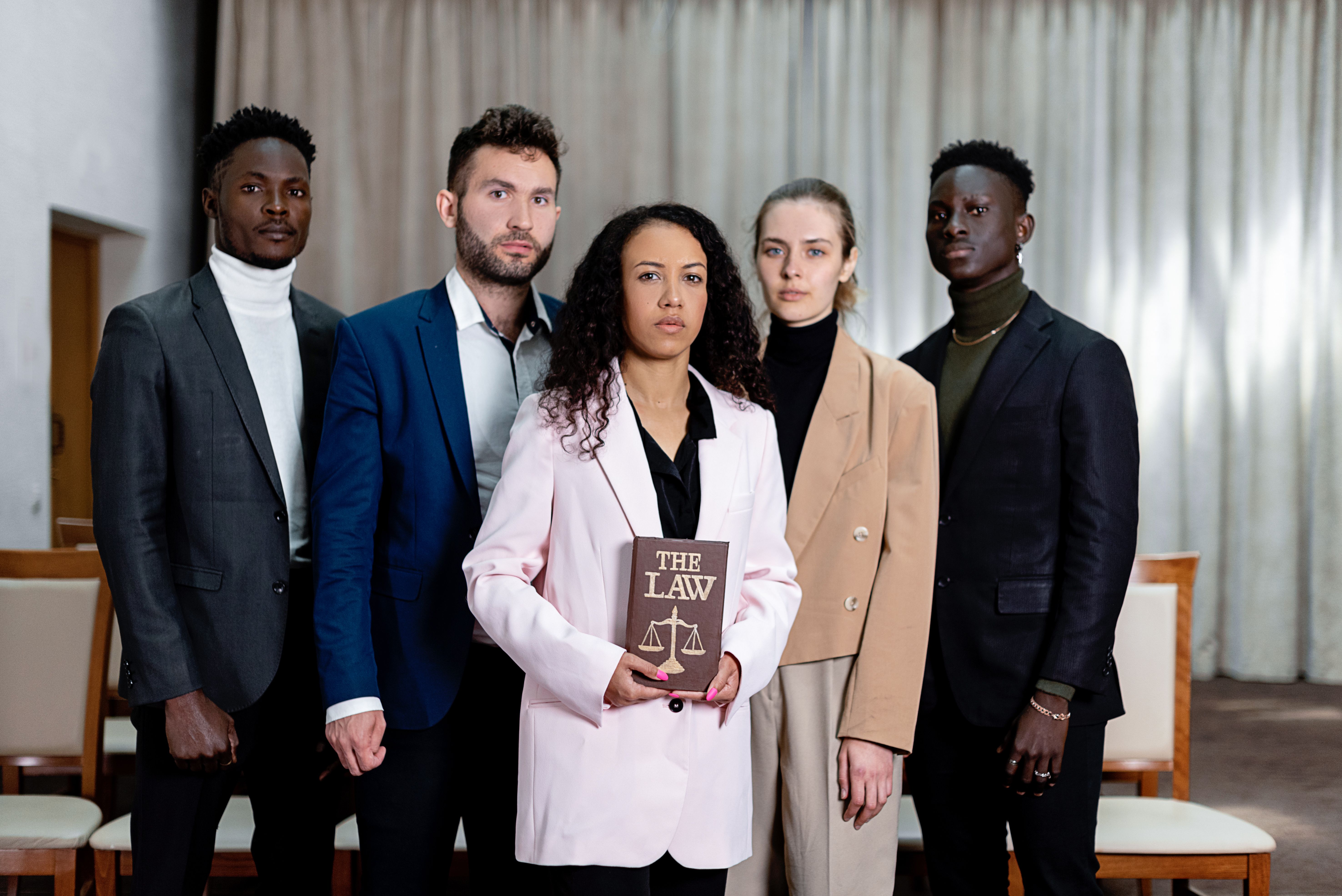 Group of five lawyers posing with a law book in an office