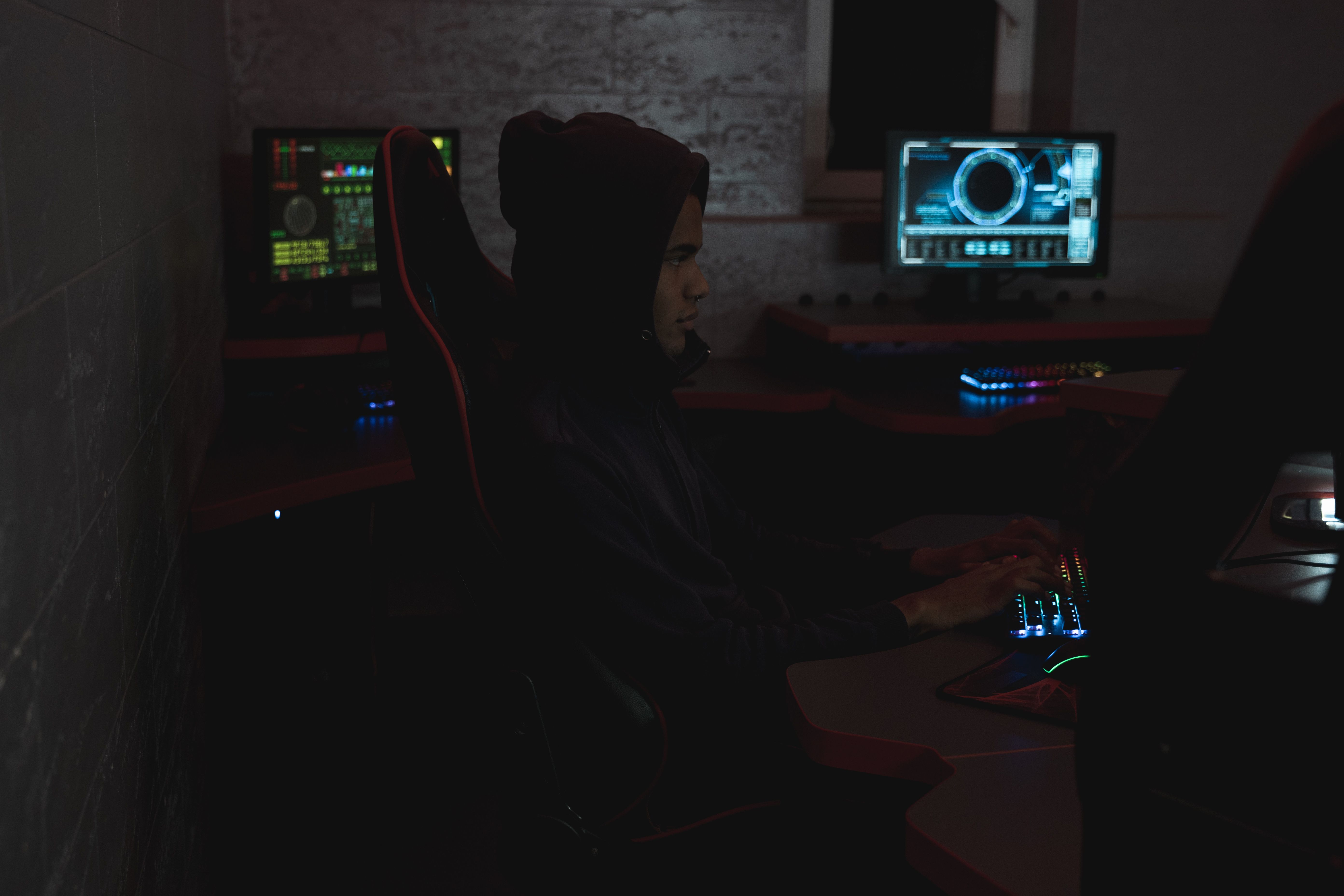 Security analyst reviewing data across multiple monitors in a dark operations environment