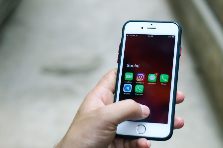 Hand holding a smartphone with social media and communication apps, representing Telegram intelligence sources