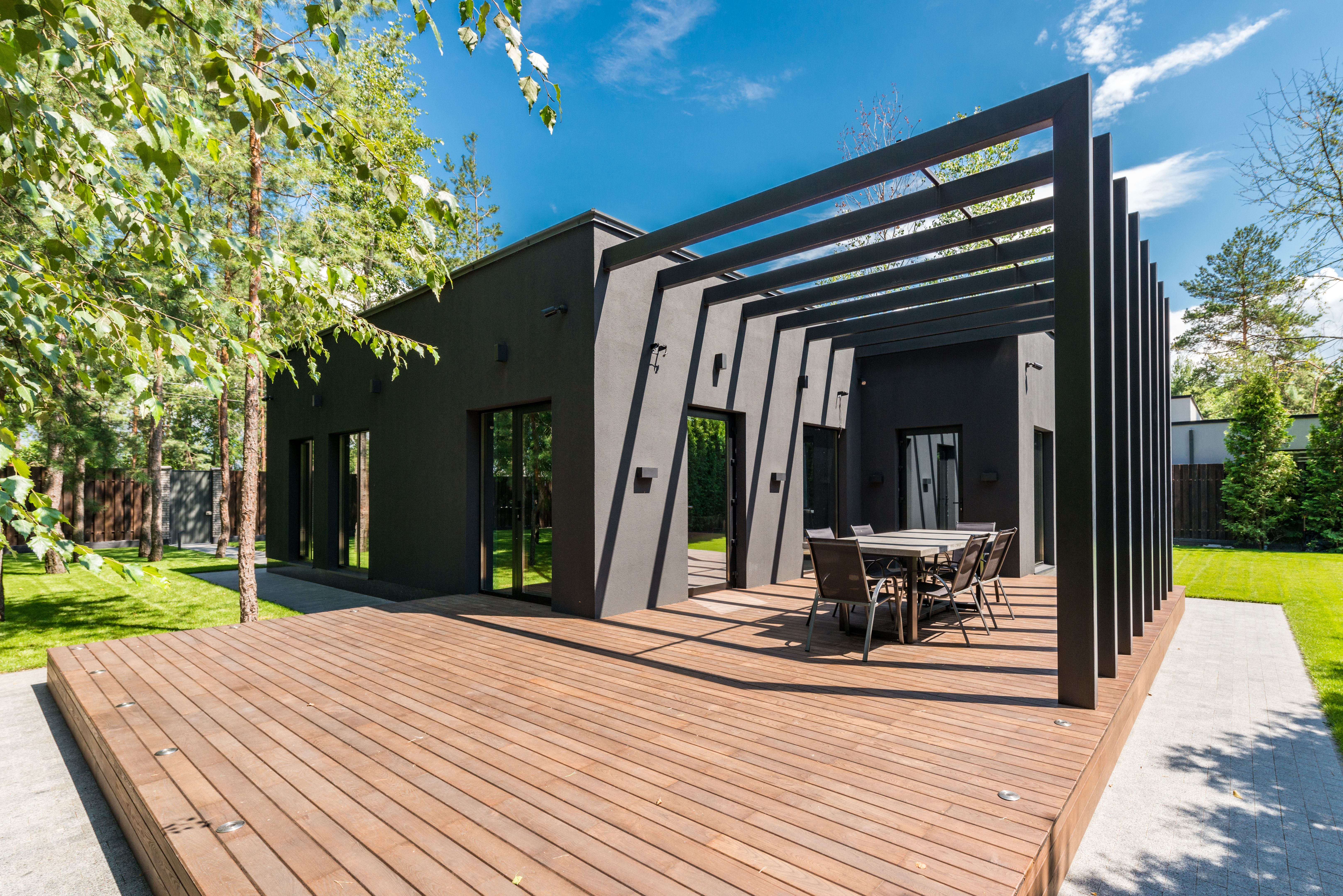 Stylish outdoor space with a timber deck and dining set surrounded by lush greenery.
