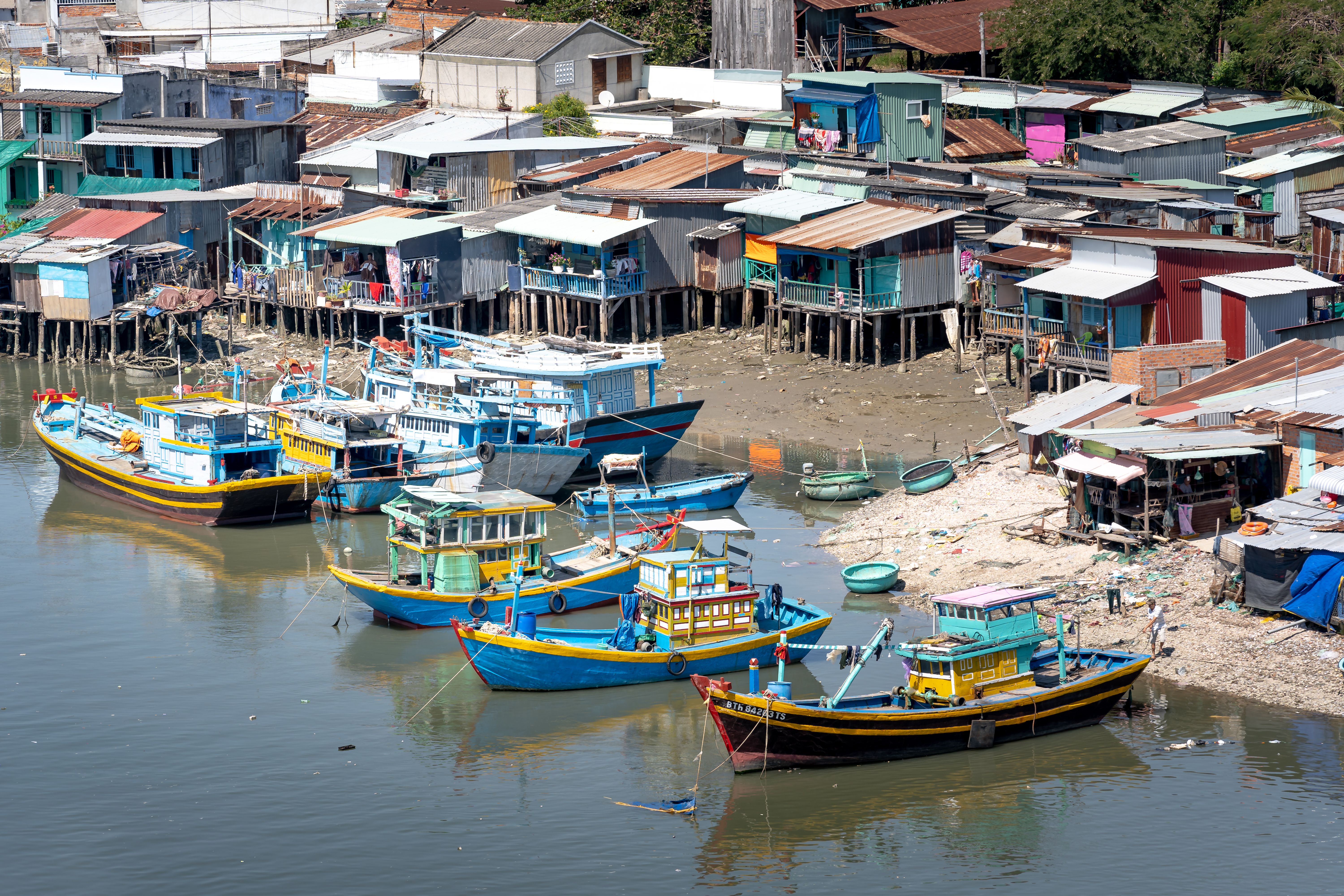 Colorful fishing boats and stilt houses in a traditional Vietnamese coastal village.