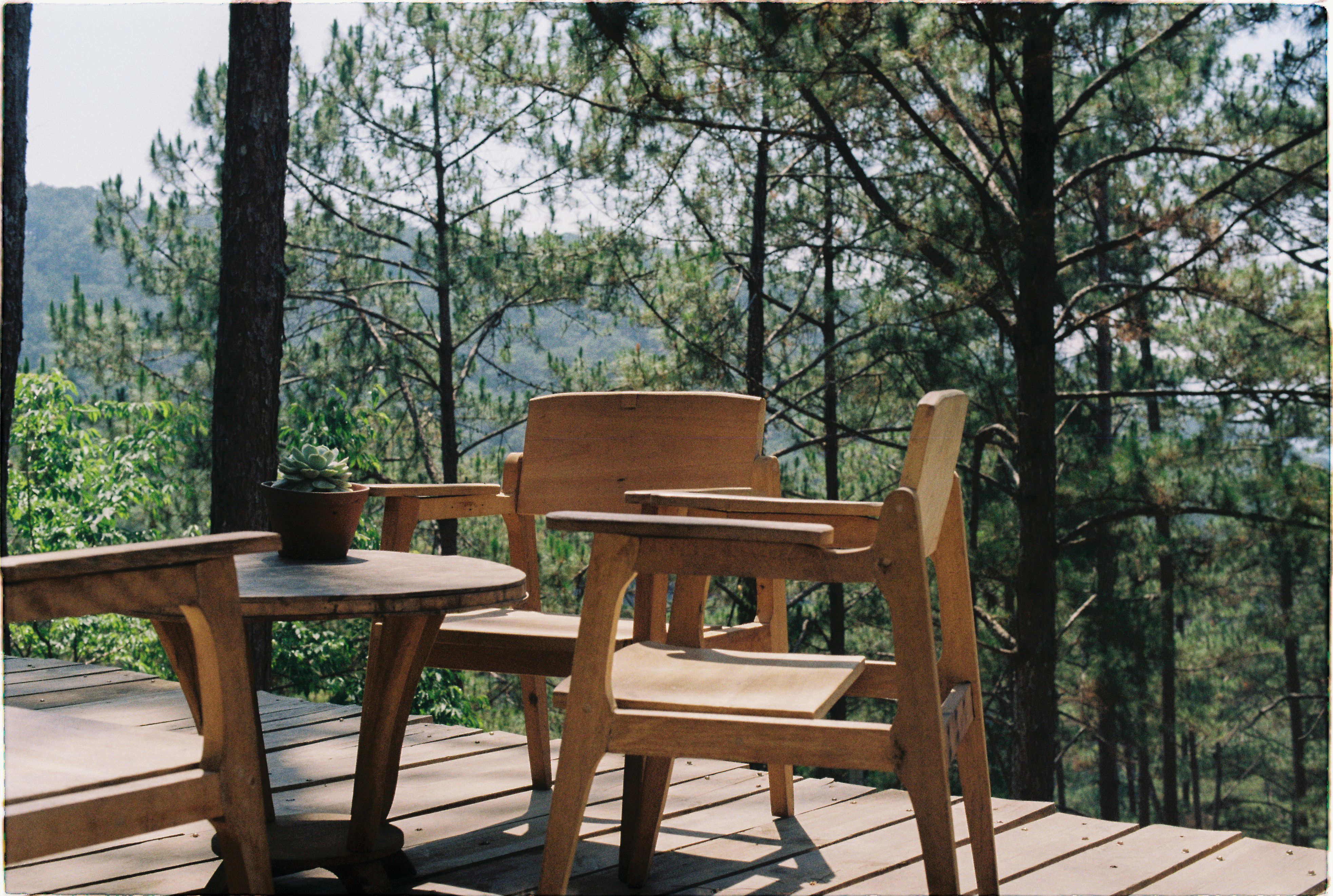 Wooden patio with chairs and a table overlooking a lush forest, showing a deck in everyday homeowner use.